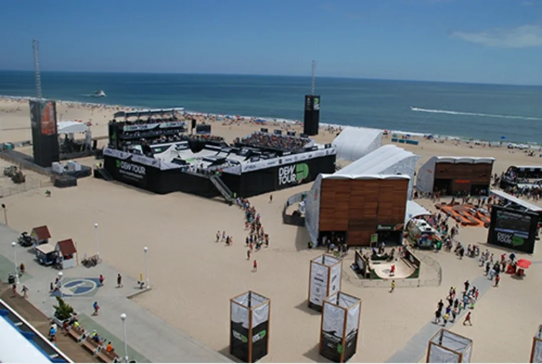 A beach with people walking around and tents on the ground.